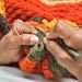A person knitting a blanket with a pair of scissors