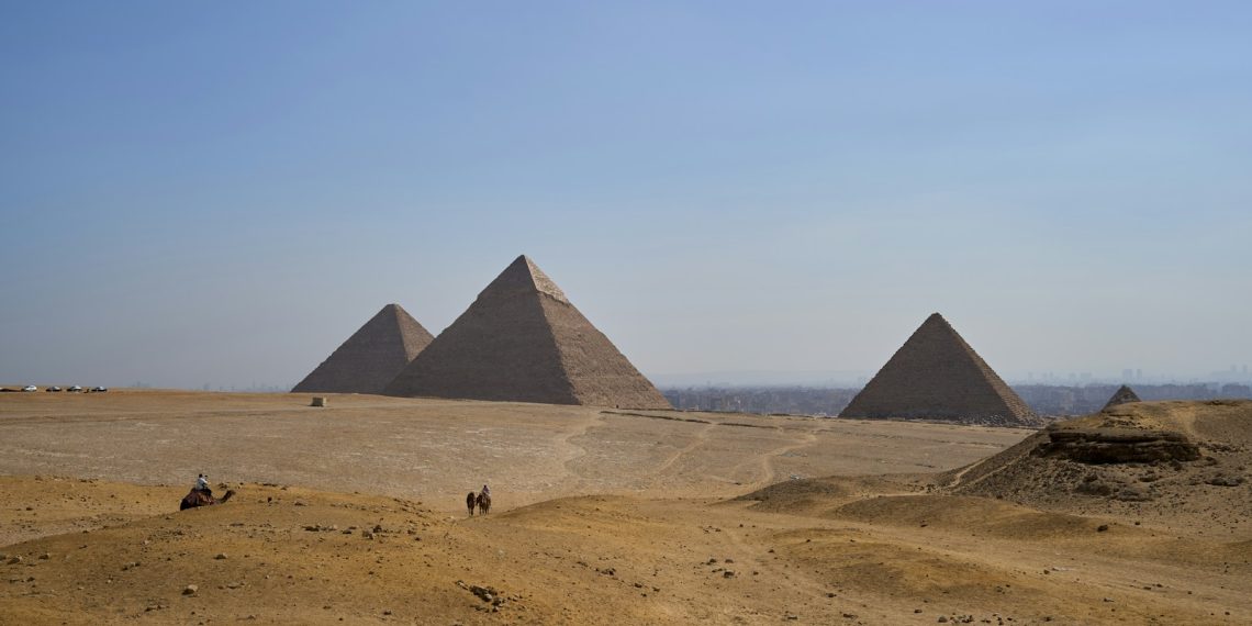 three pyramids in the desert with a sky background