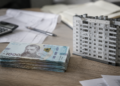 Гривневі банкноти та архітектурна модель будинку на офісному столі