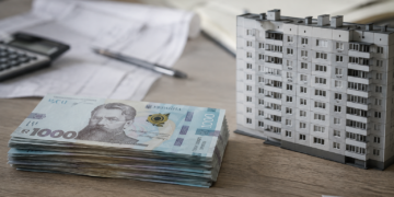 Гривневі банкноти та архітектурна модель будинку на офісному столі