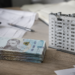 Гривневі банкноти та архітектурна модель будинку на офісному столі
