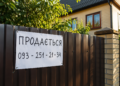 Табличка "Продається" на паркані приватного будинку
