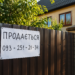 Табличка "Продається" на паркані приватного будинку